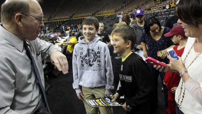 Dan Gable chats with 13-year-old Garret Robinson of Maple Park, Ill. and his 10-year-old brother, Lane, prior to the Hawkeyes' wrestling dual against Iowa State on Saturday, Nov. 29, 2014.