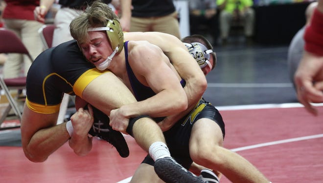 Norwalk senior 145-pounder Tyler Hirl (in black with gold headgear) wrestles Waverly-Shell Rock junior Dalton Woodyard in a Class 3A opening-round match at the state wrestling meet Feb. 16 at Wells Fargo Arena in Des Moines.