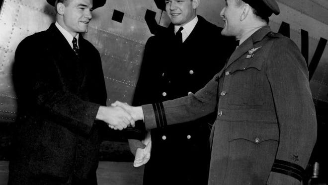 Dec. 7, 1939 - A Navy airplane bearing two top football figures of the 1939 season landed at Navy Field in Washington, D.C. Nile Kinnick (left) and Al Bergner (center), captain of the Navy team, en route to Annapolis, Md., for a visit were greeted by Commander S.P. Ginder of the Naval Air Station.