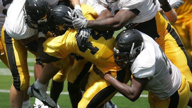 Iowa running back Jeff Brinson, center, is wrapped up by defenders, clockwise from left, Pat Angerer, Amari Spievey, Christian Ballard and Broderick Binns during an open practice for Kids Day at Kinnick Stadium in Iowa City on Saturday, Aug. 15, 2009.