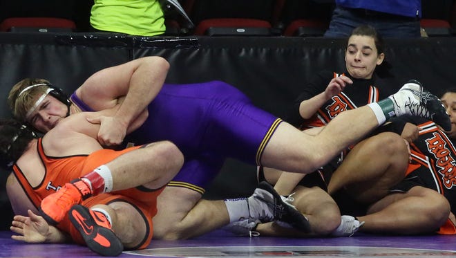 Cheerleaders scramble for safety as Indianola senior 285-pounder Eagan Lickiss (in purple) wrestles Waterloo East senior Omar Begic in a first-round match Feb. 15 at the Class 3A state tournament at Wells Fargo Arena in Des Moines.