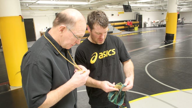 Former Hawkeye wrestling coach Dan Gable, left, and current head coach Tom Brands compare their Olympic gold medals at the Dan Gable Wrestling Complex in Carver-Hawkeye Arena on Friday, April 13, 2012. Gable wears his 1972 Olympic gold medal while Brands sports his won in the 1996 Games.