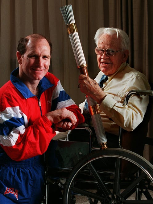 This photo was taken on May 23, 1996. Dan Gable, left, and Irving Weber, 95, both of Iowa City, were among 66 Iowa Community Hero torch bearers when the Olympic flame passed through Iowa.