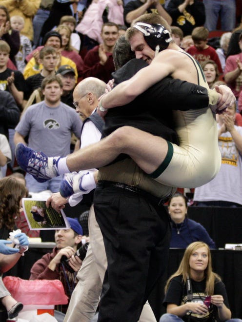 Iowa City West's Nick Moore jumps into the arms of coach Mark Reiland after defeating Indianola's Spencer BeLieu during the 160-pound Class 3A championship match at the state wrestling tournament at Wells Fargo Arena. It was the fourth consecutive state title for Moore.