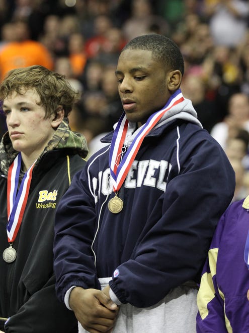 John Meeks receives his fourth state championship medal after his 138-pound match against Connor Ryan of Bettendorf.