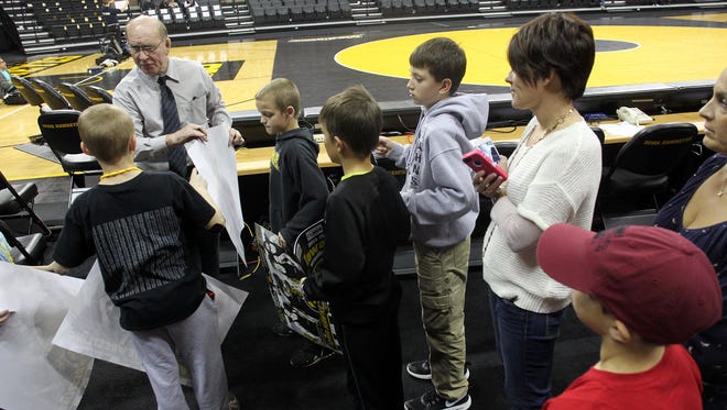 Dan Gable signs autographs for fans prior to the Hawkeyes' wrestling dual against Iowa State on Saturday, Nov. 29, 2014.