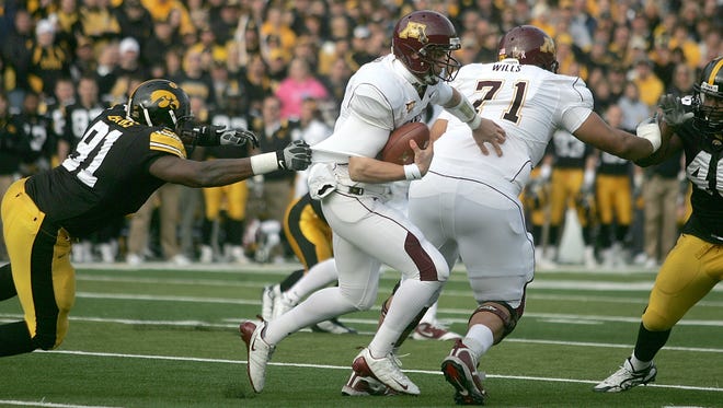 Iowa defensive end Broderick Binns, left, gets a grip on Minnesota quarterback Adam Weber as right tackle Jeff Willis blocks defensive tackle Christian Ballard, right, during the first quarter of their game Saturday, Nov. 21, 2009, in Iowa City. Iowa won the game 12-0.