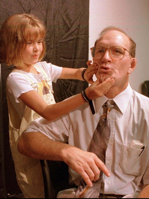 Iowa coach Dan Gable holds still as his daughter Mackenzie, 9, moves his mouth as she said, "I am not going to retire." after a news conference in Iowa City, Monday, July 14, 1997.