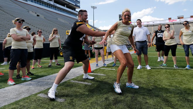 Iowa offensive lineman Ike Boettger blocks his mother. Kris, as other women and position coach Brian Ferentz look on during Saturday's event at Kinnick Stadium.