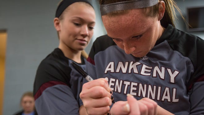 Ankeny Centennial basketball player Emily Fontana, right, writes on teammate Sydney Wycoff wrist before playing in the state tournament at Wells Fargo Arena in Des Moines, Iowa, on Wednesday, March 2, 2016. They both lost their parents to brain cancer in the past year. In their memory, they write the initials of their late parents, Amy Staggs-Fontana and Greg Wycoff, on their wrists before each game.