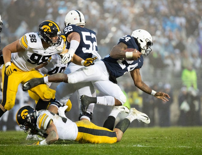 Miles Sanders #24 of the Penn State Nittany Lions is tackled by Amani Hooker #27 of the Iowa Hawkeyes during a game at Beaver Stadium on Saturday, October 27, 2018, in State College, Pennsylvania.