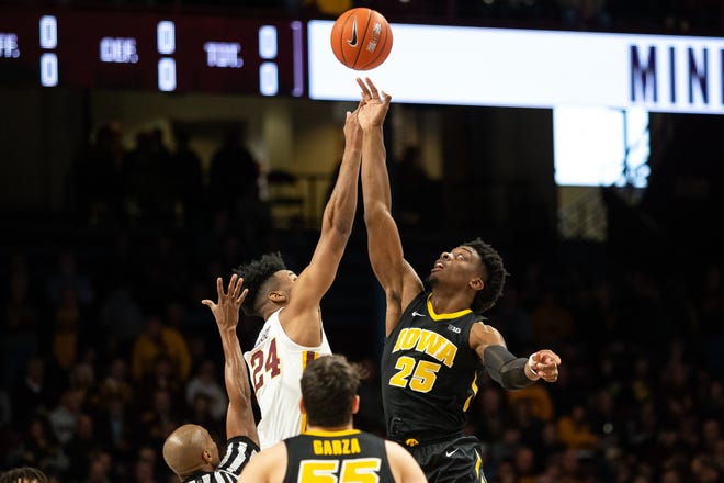 Iowa Hawkeyes forward Tyler Cook (25) and Minnesota Gophers forward Eric Curry (24) battle for the ball during the first half at Williams Arena.
