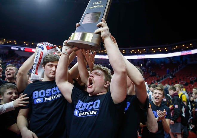 Members of the Don Bosco wrestling team raise the Class 1A state championship trophy during the 2019 Iowa high school dual wrestling state tournament on Wednesday, Feb. 13, 2019, at Wells Fargo Arena in Des Moines.