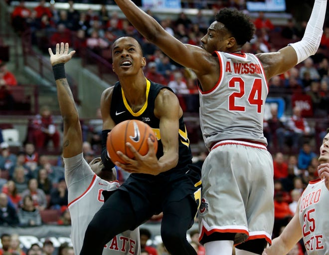 Iowa guard Maishe Dailey, center, goes up for a shot between Ohio State forward Luther Muhammad, left, and forward Andre Wesson during the first half of an NCAA college basketball game in Columbus, Ohio, Tuesday, Feb. 26, 2019.
