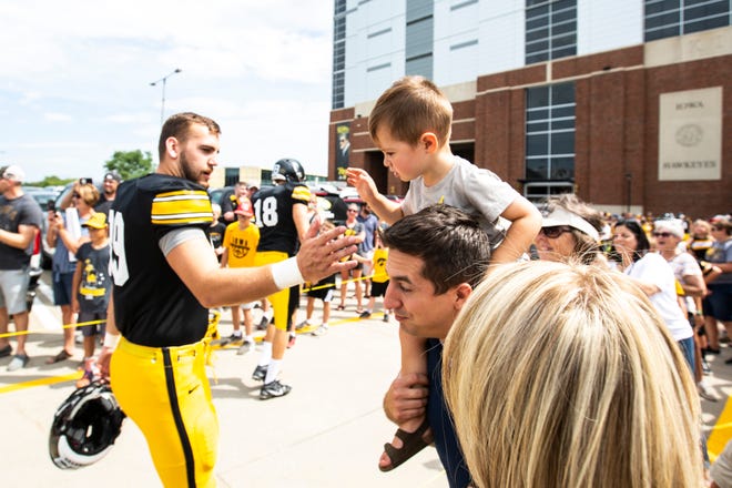 Carson Fridono, 2, goes for a high-five while resting on the shoulders of his father Elliot, while visiting the game with his mom, Sarah Fridono, and sisters Shealyn and Natalie before a Hawkeyes football Kids Day scrimmage, Saturday, Aug. 10, 2019, at Kinnick Stadium in Iowa City, Iowa.