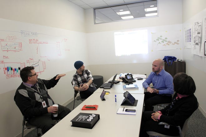 A group of employees discuss ways to optimize mobile platforms at the ACT campus on Wednesday, April 26, 2014.