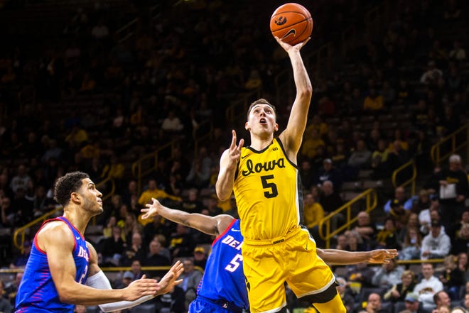 Iowa guard CJ Fredrick (5) makes a layup as DePaul's Jaylen Butz, left, and Jalen Coleman-Lands defend during a NCAA non-conference men's basketball game, Monday, Nov., 11, 2019, at Carver-Hawkeye Arena in Iowa City, Iowa.
