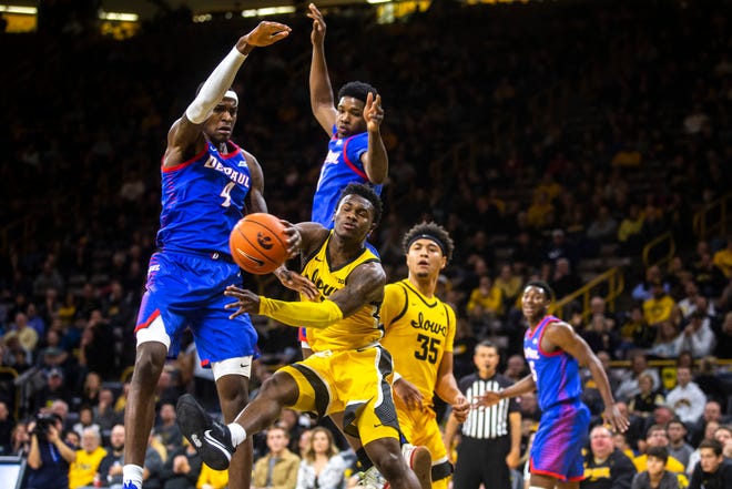 Iowa guard Joe Toussaint (1) shovels a pass out from in the paint as DePaul's Paul Reed (4) and Romeo Weems defend during a NCAA non-conference men's basketball game, Monday, Nov., 11, 2019, at Carver-Hawkeye Arena in Iowa City, Iowa.