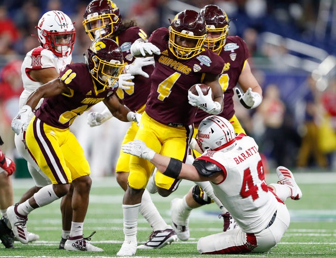 Central Michigan running back Kobe Lewis carries the ball while Miami (Ohio) defensive back Bart Baratti tries to make a tackle during the second quarter in the MAC Championship game at Ford Field.