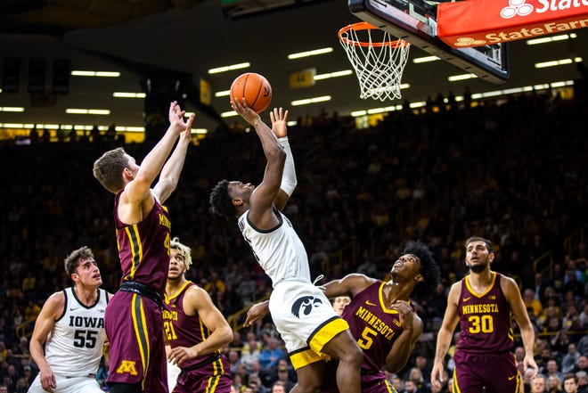 Iowa guard Joe Toussaint (1) puts up a shot as Minnesota's Michael Hurt, left, and Marcus Carr (5) defend during a NCAA Big Ten Conference men's basketball game, Monday, Dec. 9, 2019, at Carver-Hawkeye Arena in Iowa City, Iowa.