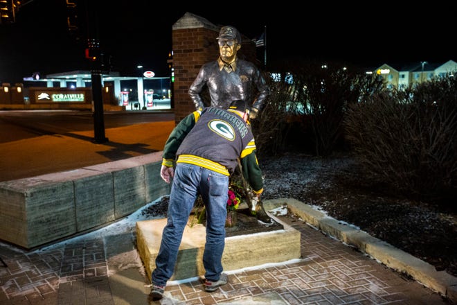 A mourner rests flowers at the feet of a statue of former Iowa Hawkeyes football head coach Hayden Fry, Tuesday, Dec. 17, 2019, along 1st Avenue/Hayden Fry Way in Coralville, Iowa. Fry died Dec. 17, he was 90 years old.