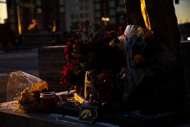 Flowers and a pair of yellow sunglasses rest at the feet of a statue of former Iowa Hawkeyes football head coach Hayden Fry is pictured as the sun rises, Wednesday, Dec. 18, 2019, along First Avenue/Hayden Fry Way near the Iowa City/Coralville Area Convention & Visitors Bureau in Coralville, Iowa. Fry died Dec. 17, he was 90 years old.