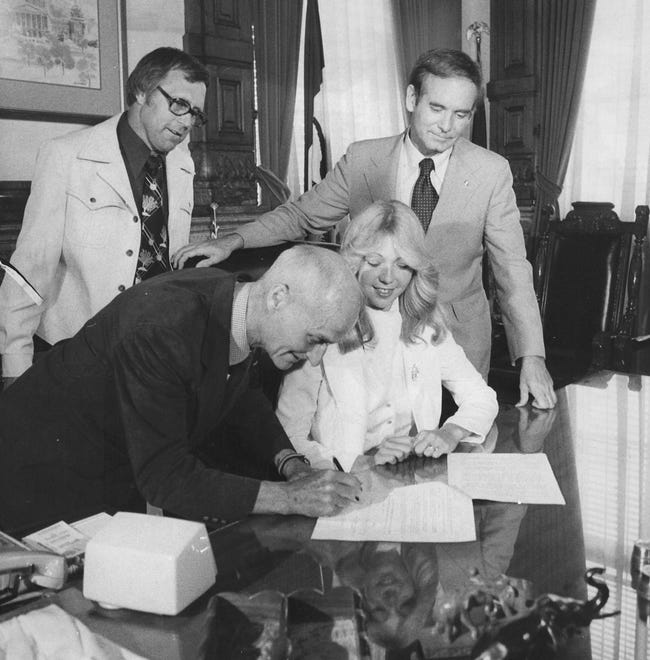From 1978: George Nissen of Cedar Rapids signs Molly Bolin's contract at Bolin, Rod Lein of Ankeny (back left) and Iowa Gov. Robert Ray wach in the governor's office. Nissen was owner and Lein general manager of the Iowa Cornets of the new professional Women's Basketball League. Bolin, a former Moravia High School and Grand View College star, was the first to sign with the Cornets.