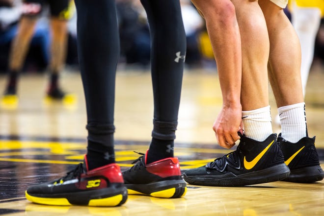 Iowa center Luka Garza ties his shoes while a teammate gets ready to shoot a free throw during a NCAA college Big Ten Conference men's basketball game, Friday, Jan. 10, 2020, at Carver-Hawkeye Arena in Iowa City, Iowa.