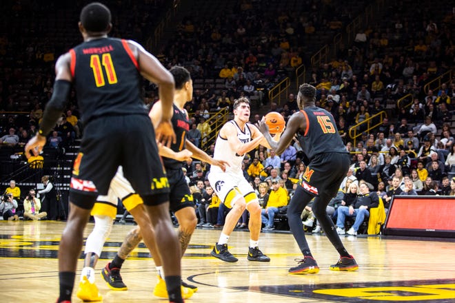 Iowa center Luka Garza (55) makes a 3-point basket as Maryland center Chol Marial (15) defends during a NCAA college Big Ten Conference men's basketball game, Friday, Jan. 10, 2020, at Carver-Hawkeye Arena in Iowa City, Iowa.
