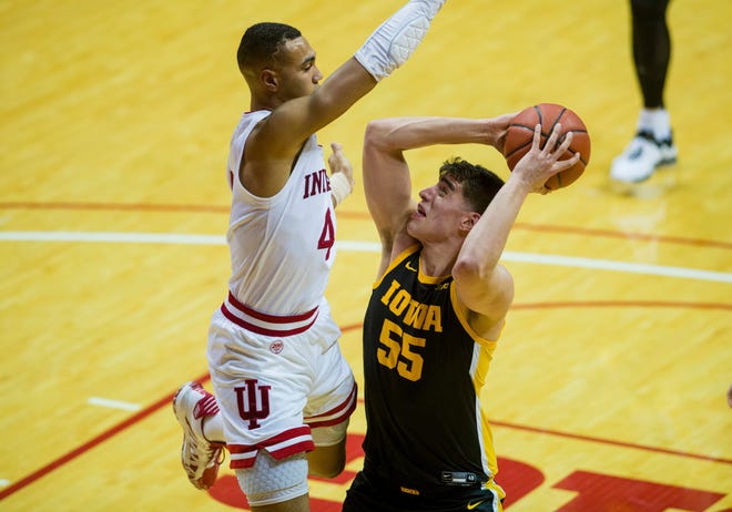 Iowa center Luka Garza (55) works to get a shot away as he is defended by Indiana forward Trayce Jackson-Davis (4) during the second half of an NCAA college basketball game, Thursday, Feb. 13, 2020, in Bloomington, Ind. (AP Photo/Doug McSchooler)