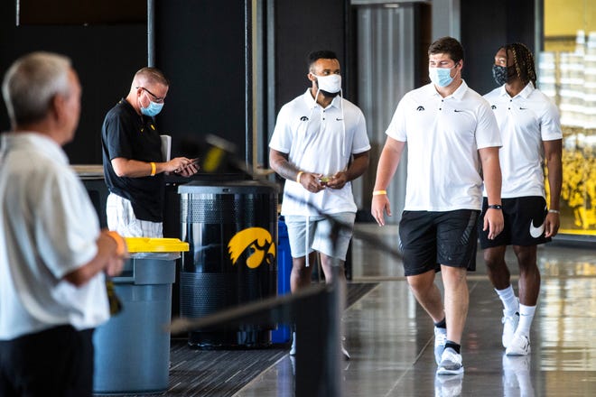 Iowa football players, from center left, Djimon Colbert, Tyler Linderbaum, and Brandon Smith wear face masks as they arrive before speaking during a news conference, Thursday, July 16, 2020, at the Pacha Family Club Room in the north end zone of Kinnick Stadium in Iowa City, Iowa.