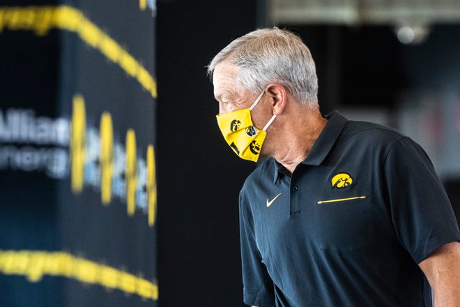 Iowa head coach Kirk Ferentz wears a face mask featuring Tigerhawk logos and football helmets as he walks up to the podium before speaking during a news conference amid the novel coronavirus pandemic, Thursday, July 16, 2020, at the Pacha Family Club Room in the north end zone of Kinnick Stadium in Iowa City, Iowa.