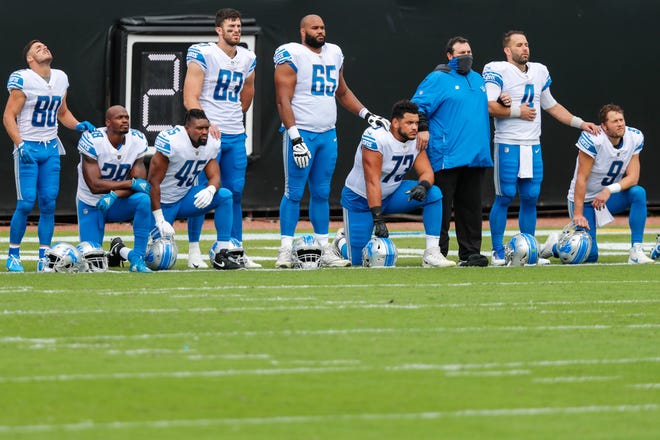 Members of the Detroit Lions including Matthew Stafford (9), Danny Amendola (80), Adrian Peterson (28), and Tyrell Crosby (65) look on during the National Anthem before the start of the game against the Jacksonville Jaguars at TIAA Bank Field on Oct. 18, 2020 in Jacksonville, Florida.