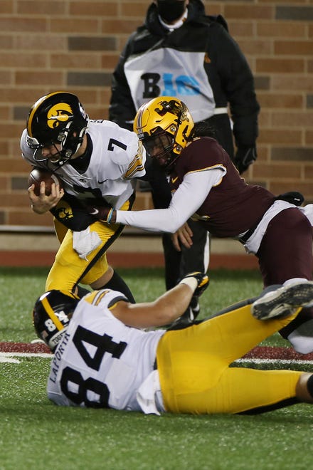 Minnesota defensive back Michael Dixon, top right, tackles Iowa quarterback Spencer Petras (7) during the second half of an NCAA college football game Friday, Nov. 13, 2020, in Minneapolis. Iowa won 35-7. (AP Photo/Stacy Bengs)