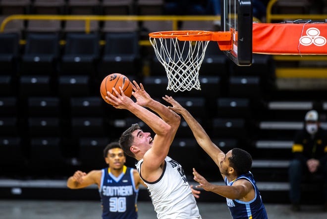 Iowa center Luka Garza (55) makes a basket as Southern University's Isaiah Rollins defends during a NCAA non-conference men's basketball game, Friday, Nov. 27, 2020, at Carver-Hawkeye Arena in Iowa City, Iowa.