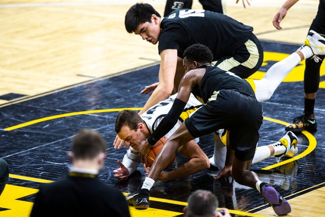 Iowa forward Jack Nunge fights for a loose ball against Purdue center Zach Edey (15) and Purdue guard Eric Hunter Jr.  during a NCAA Big Ten Conference men's basketball game, Tuesday, Dec. 22, 2020, at Carver-Hawkeye Arena in Iowa City, Iowa.