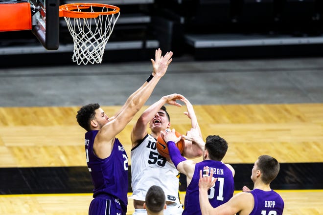 Iowa center Luka Garza (55) gets fouled by Northwestern forward Robbie Beran (31) as Northwestern's Pete Nance, left, defends during a NCAA Big Ten Conference men's basketball game, Tuesday, Dec. 29, 2020, at Carver-Hawkeye Arena in Iowa City, Iowa.