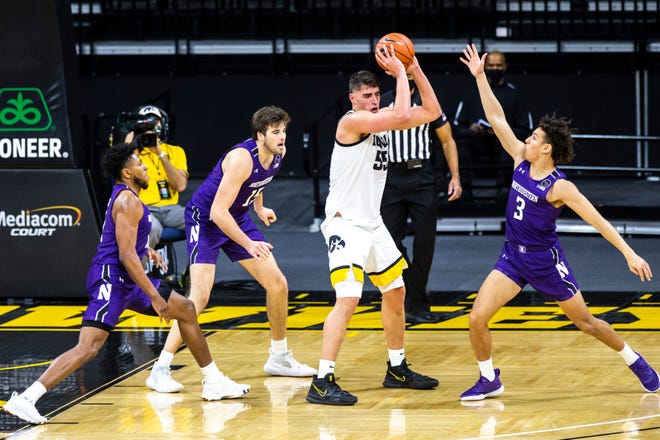 Iowa center Luka Garza (55) looks to pass as Northwestern guard Anthony Gaines, left, Northwestern center Ryan Young, second from left, and Northwestern guard Ty Berry (3) defend during a NCAA Big Ten Conference men's basketball game, Tuesday, Dec. 29, 2020, at Carver-Hawkeye Arena in Iowa City, Iowa.