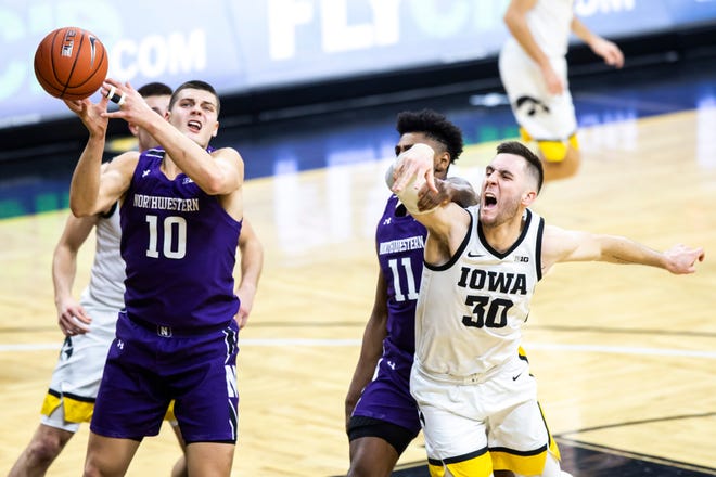 Northwestern forward Miller Kopp (10) grabs a rebound against Iowa's Connor McCaffery (30) and Northwestern guard Anthony Gaines (11) defends during a NCAA Big Ten Conference men's basketball game, Tuesday, Dec. 29, 2020, at Carver-Hawkeye Arena in Iowa City, Iowa.