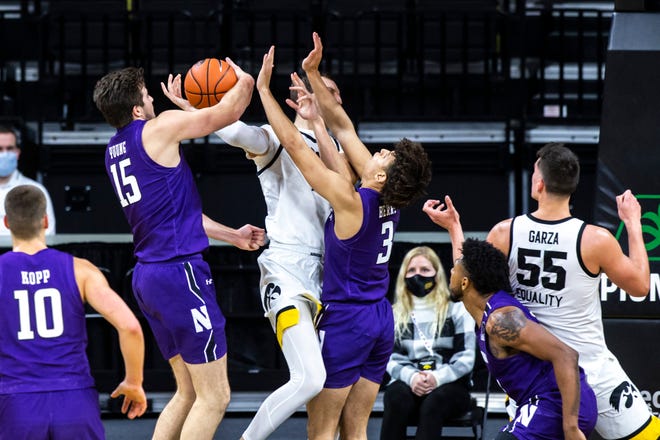 Iowa forward Jack Nunge gets fouled by Northwestern guard Ty Berry (3) as Northwestern center Ryan Young (15) defends during a NCAA Big Ten Conference men's basketball game, Tuesday, Dec. 29, 2020, at Carver-Hawkeye Arena in Iowa City, Iowa.