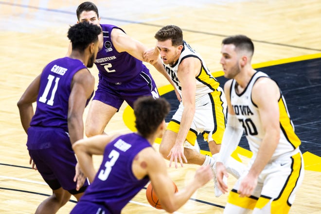 Iowa guard Jordan Bohannon drives to the basket against Northwestern guard Ryan Greer (2) and Northwestern guard Anthony Gaines (11) during a NCAA Big Ten Conference men's basketball game, Tuesday, Dec. 29, 2020, at Carver-Hawkeye Arena in Iowa City, Iowa.