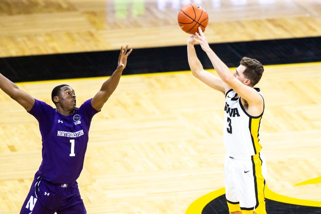 Iowa guard Jordan Bohannon (3) makes a 3-point basket as Northwestern guard Chase Audige (1) defends during a NCAA Big Ten Conference men's basketball game, Tuesday, Dec. 29, 2020, at Carver-Hawkeye Arena in Iowa City, Iowa.