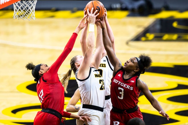 Iowa center Monika Czinano (25) grabs a rebound against Rutgers center Sakima Walker (12) and Rutgers guard Liz Martino (2) during a NCAA Big Ten Conference women's basketball game, Thursday, Dec. 31, 2020, at Carver-Hawkeye Arena in Iowa City, Iowa.