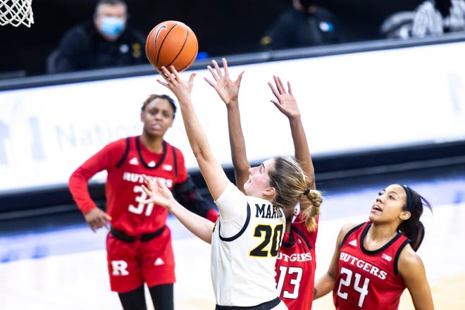 Iowa guard Kate Martin (20) makes a basket as Rutgers forward Mael Gilles (13) and Rutgers guard Arella Guirantes (24) defend during a NCAA Big Ten Conference women's basketball game, Thursday, Dec. 31, 2020, at Carver-Hawkeye Arena in Iowa City, Iowa.