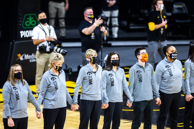 Iowa coaches, from left, special assistant to the head coach Jenni Fitzgerald, head coach Lisa Bluder and associate head coach Jan Jensen hold hands as the national anthem is played before a NCAA Big Ten Conference women's basketball game against Rutgers, Thursday, Dec. 31, 2020, at Carver-Hawkeye Arena in Iowa City, Iowa.