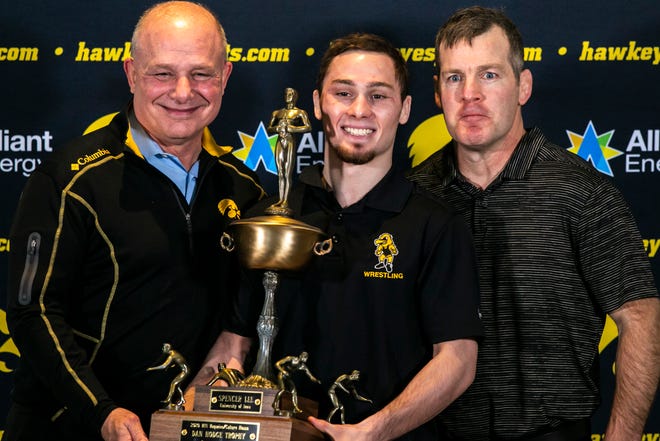 Iowa 125-pound wrestler Spencer Lee, center, poses for a photo with the 2020 Dan Hodge Trophy with his father Larry Lee, left, and Iowa head coach Tom Brands during Hawkeyes wrestling media day, Tuesday, Jan. 5, 2021, at the McCord Club level of Kinnick Stadium in Iowa City, Iowa.