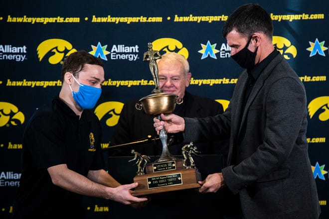 Iowa 125-pound wrestler Spencer Lee, left, is presented with the 2020 Dan Hodge Trophy by Bryan Van Kley of WIN Magazine, right, and Mike Chapman, center, during Hawkeyes wrestling media day, Tuesday, Jan. 5, 2021, at the McCord Club level of Kinnick Stadium in Iowa City, Iowa.