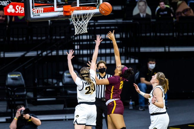 Minnesota center Klarke Sconiers, center, makes a basket as Iowa guard Kate Martin, left, and Iowa center Monika Czinano, right, defend during a NCAA Big Ten Conference women's basketball game, Wednesday, Jan. 6, 2021, at Carver-Hawkeye Arena in Iowa City, Iowa.