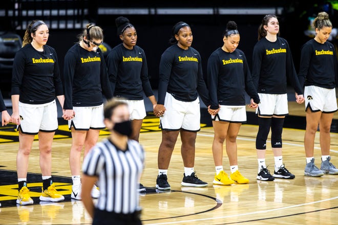 Iowa Hawkeyes players wear shirts reading, "Inclusion." as they hold hands while the national anthem is played before a NCAA Big Ten Conference women's basketball game, Wednesday, Jan. 6, 2021, at Carver-Hawkeye Arena in Iowa City, Iowa.