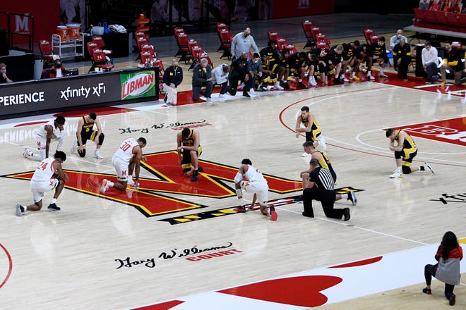 Maryland and Iowa players take a knee before the tipoff of an NCAA college basketball game Jan. 7 in College Park, Maryland.
